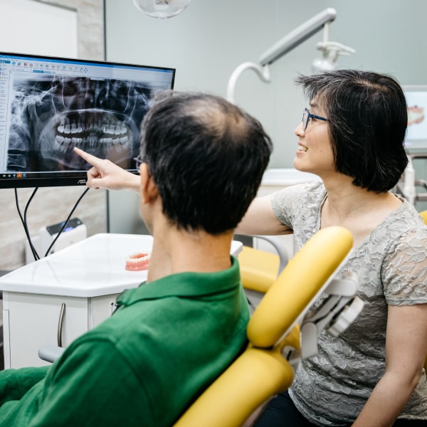 Doctor Lai explains the plan of action to the patient, pointing to the X-ray of his jaw